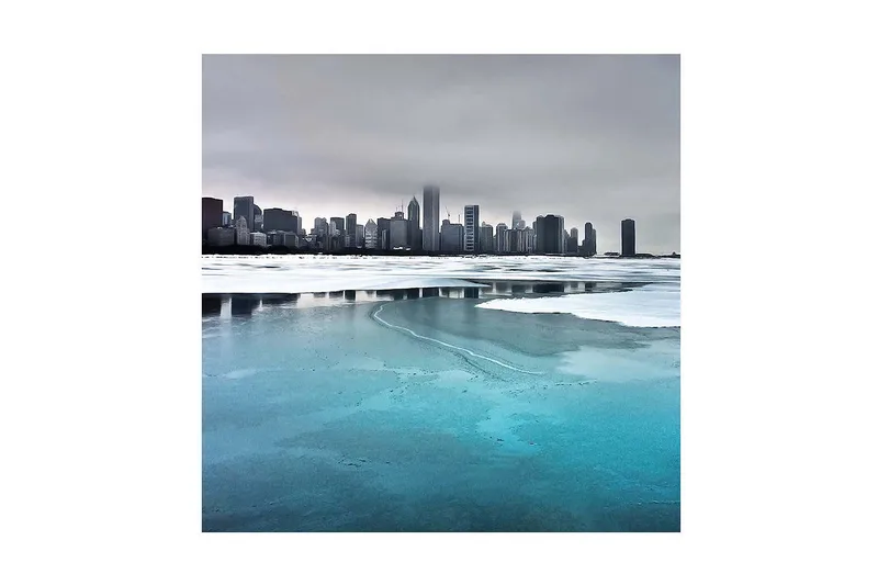Canvas-taulu 45x45 cm - Rannikko jäätyneillä järvillä ja taustalla kaupunkisiluetti, Jäänsininen / Harmaa / Valkoinen