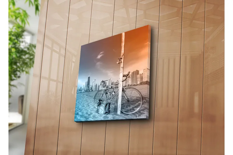 Canvas-taulu 45x45 cm - Polkupyörä nojaa tolppaan, taustalla kaupungin siluetti - Sininen / oranssi - Sisustustuotteet - Taulu & taide - Canvas-taulu