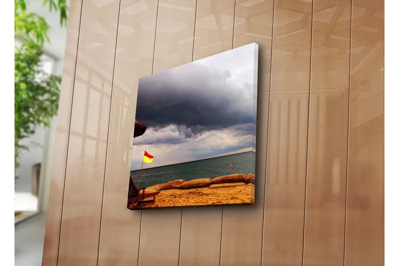 Canvas-taulu 45x45 cm - Punainen ja keltainen lippu rannalla, taustalla tummia pilviä - Tummanharmaa / Punainen / Keltainen - Sisustustuotteet - Taulu & taide - Canvas-taulu