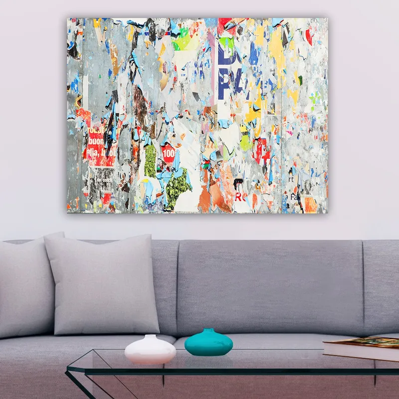 Canvas taulu 70x100 cm - Abstrakti sommitelma värikkäistä, kuluneista julisteista ja tarroista, jotka luovat dynaamisen ja teksturoidun pinnan, Harmaa / Sininen / Oranssi