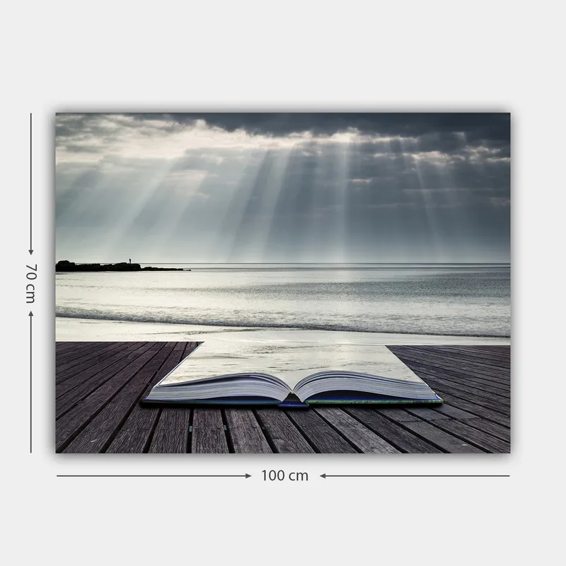 Canvas taulu 70x100 cm - Avoin kirja puisella laiturilla meren rannalla, pilvisen taivaan pehmeiden valonsäteiden ympäröimänä - Harmaa / Sininen / Valkoinen - Sisustustuotteet - Taulu & taide - Canvas-taulu