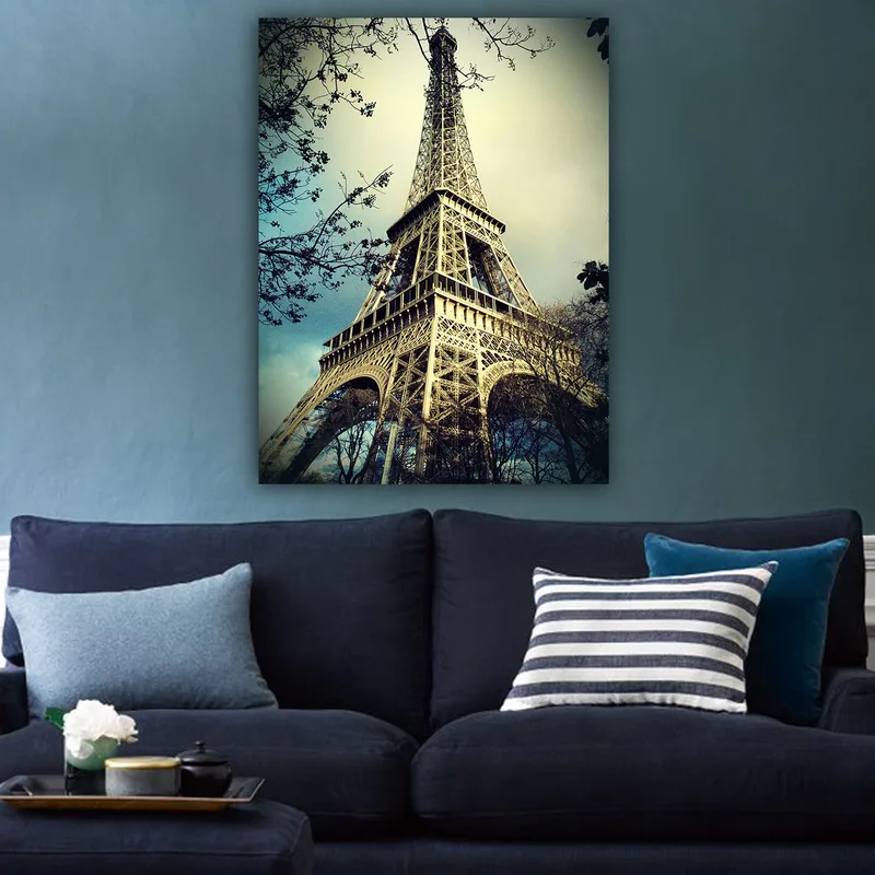 Canvas taulu 70x100 cm - Eiffel-torni Pariisissa, matalasta kulmasta kuvattuna, ympäröiden puiden oksia - Harmaa / Beige / Sininen - Sisustustuotteet - Taulu & taide - Canvas-taulu