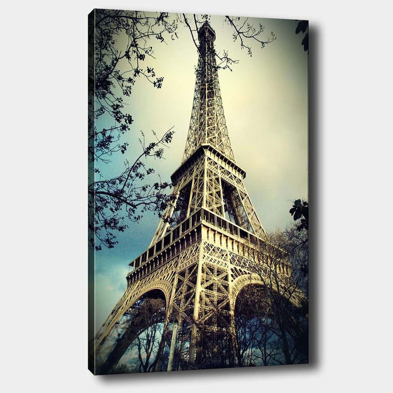 Canvas taulu 70x100 cm - Eiffel-torni Pariisissa, matalasta kulmasta kuvattuna, ympäröiden puiden oksia, Harmaa / Beige / Sininen