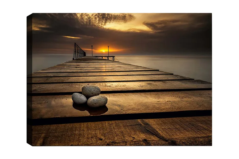 Canvas taulu 70x100 cm - Hiljainen laituri auringonlaskussa, etualalla kiviä, Kulta / Ruskea / Harmaa
