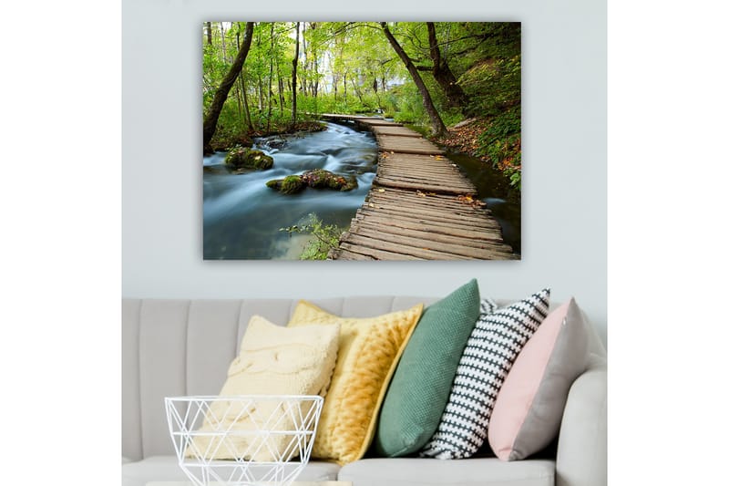 Canvas taulu 70x100 cm - Hiljainen metsäpolku mutkittelee solinaavan puron yli rehevien puiden ja kasvillisuuden ympäröimänä - Vihreä / Ruskea / Sininen - Sisustustuotteet - Taulu & taide - Canvas-taulu
