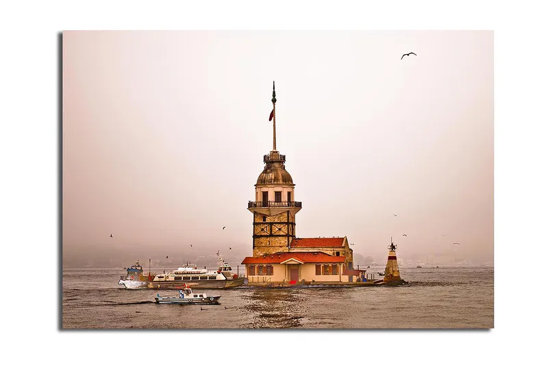 Canvas taulu 70x100 cm - Historiallinen majakka kohoaa veden ylle sumuisessa tunnelmassa, Beige / Oranssi / Ruskea