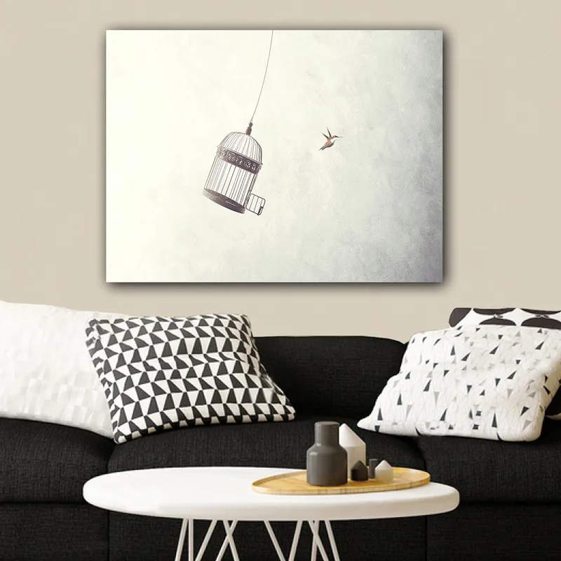 Canvas taulu 70x100 cm - Ilmassa roikkuva lintuhäkki ja lähellä lentävä lintu, Harmaa / Musta / Valkoinen