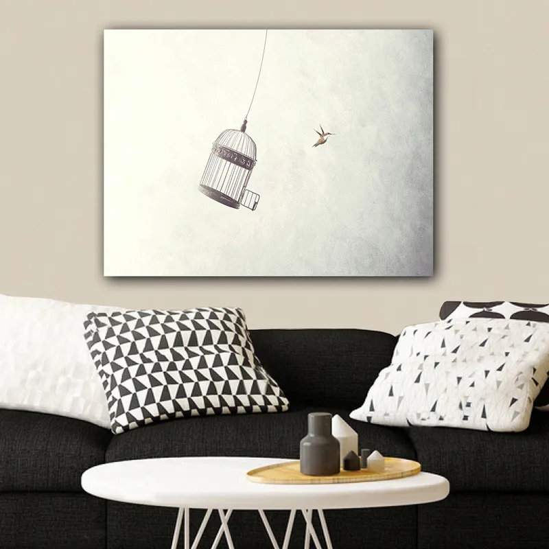 Canvas taulu 70x100 cm - Ilmassa roikkuva lintuhäkki ja lähellä lentävä lintu, Harmaa / Musta / Valkoinen