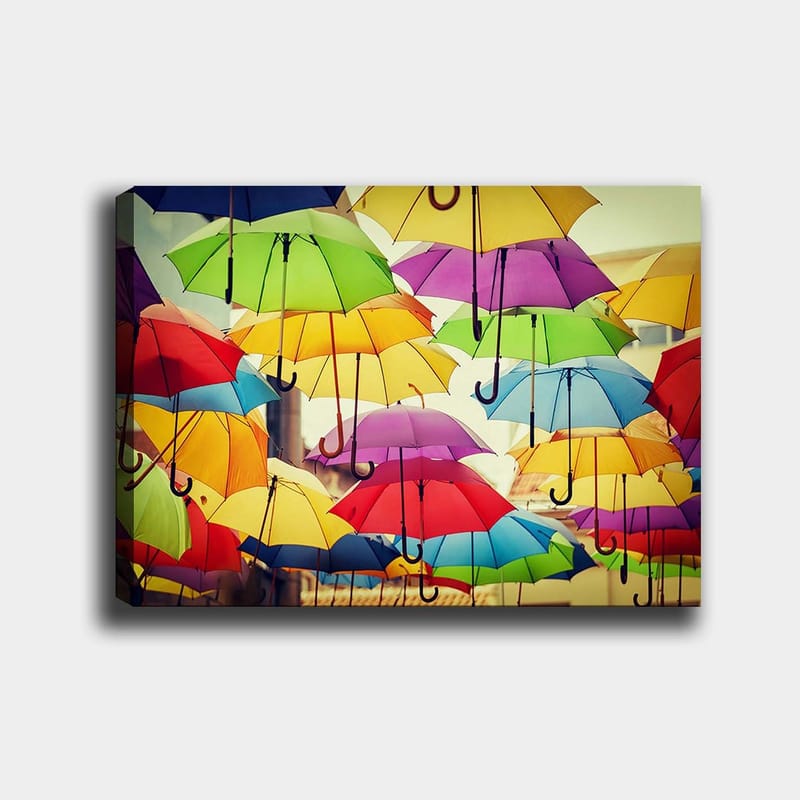 Canvas taulu 70x100 cm - Ilmassa roikkuvat värikkäät sateenvarjot luovat eloisan ja leikkisän tunnelman, Vihreä / Keltainen / Punainen
