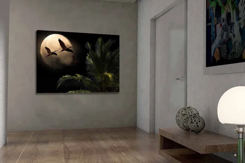 Canvas taulu 70x100 cm - Kaksi lintua lentää kohti suurta kuuta palmun kaltaisen kasvin yllä, Tummanvihreä / Harmaa / Beige