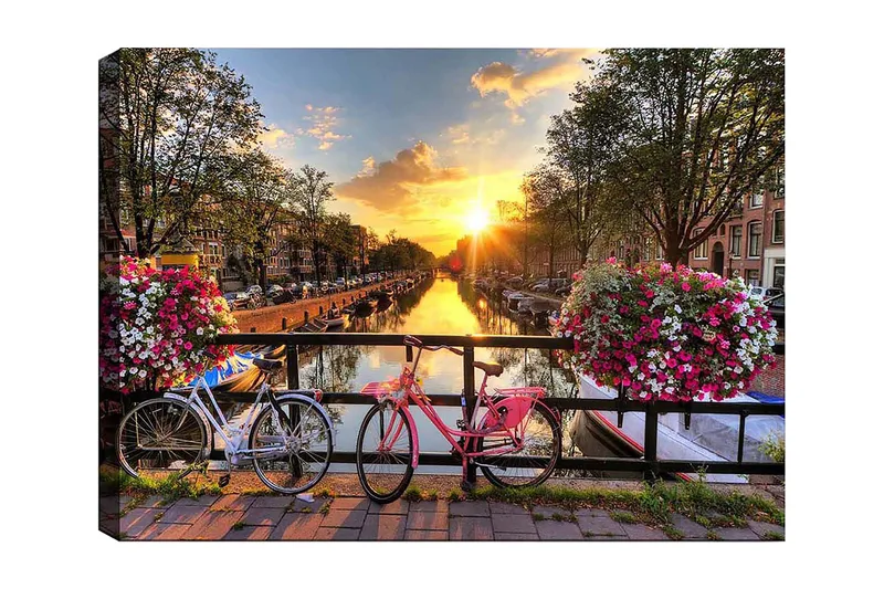 Canvas taulu 70x100 cm - Kaksi polkupyörää viehättävässä kanavamaisemassa kukkien ja auringonlaskun keskellä, Vaaleanpunainen / Valkoinen / Vihreä