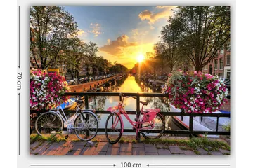 Canvas taulu 70x100 cm - Kaksi polkupyörää viehättävässä kanavamaisemassa kukkien ja auringonlaskun keskellä - Vaaleanpunainen / Valkoinen / Vihreä - Sisustustuotteet - Taulu & taide - Canvas-taulu
