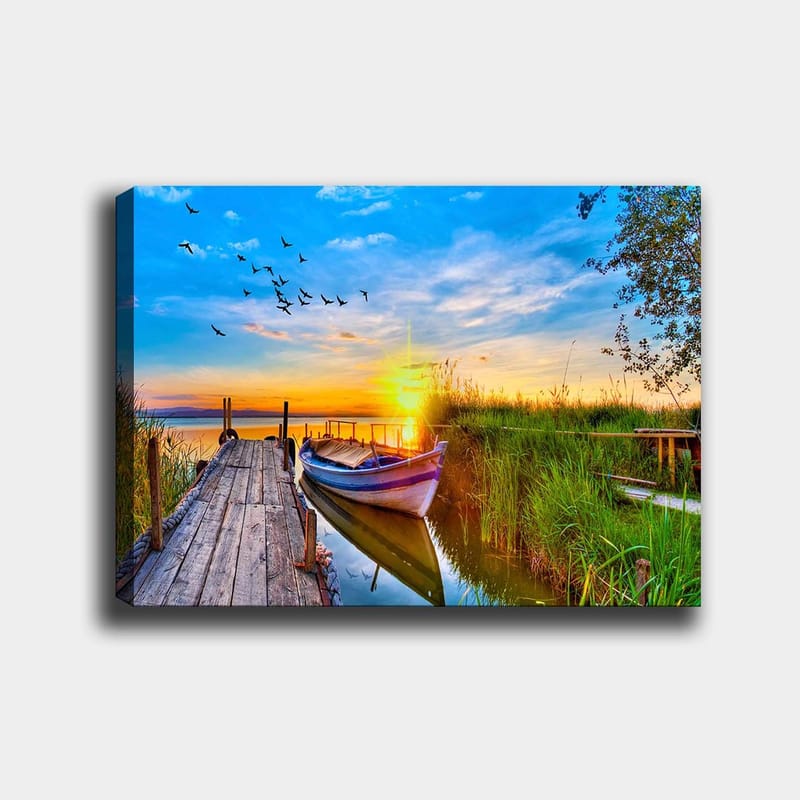 Canvas taulu 70x100 cm - Kaunis auringonlasku rauhallisen järven yllä, vene puisella laiturilla vehreyden ympäröimänä, Sininen / Oranssi / Vihreä