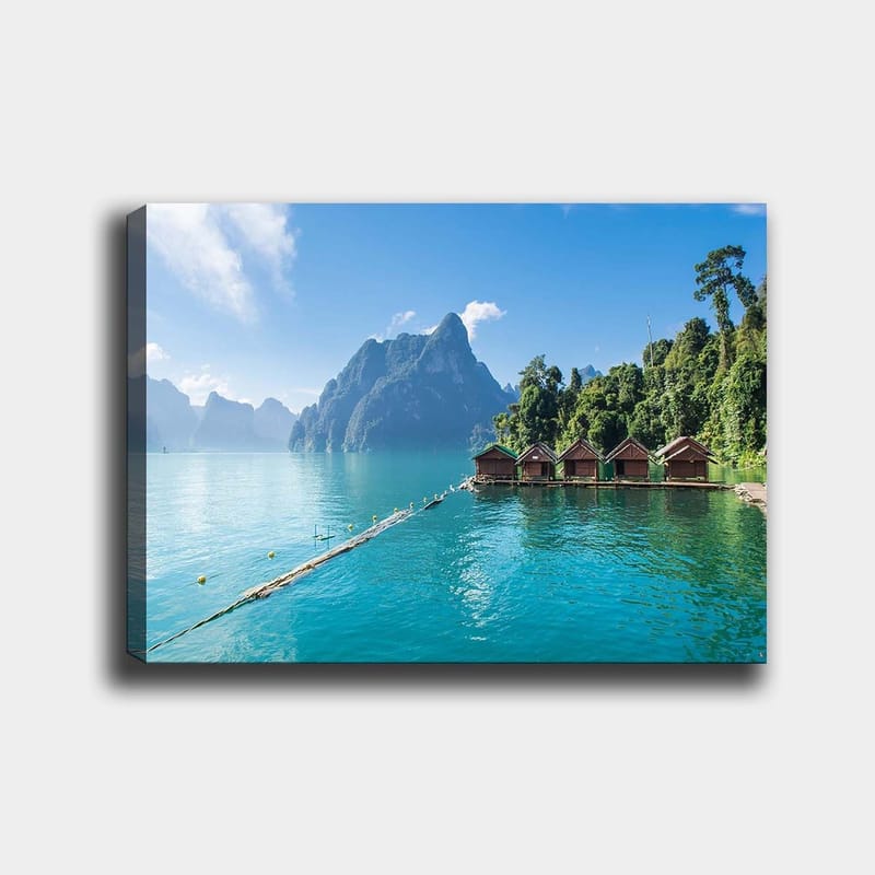 Canvas taulu 70x100 cm - Kaunis järvi mökkineen veden äärellä, majesteettisten vuorten ja rehevän metsän ympäröimänä, Turkoosi / Vihreä / Ruskea