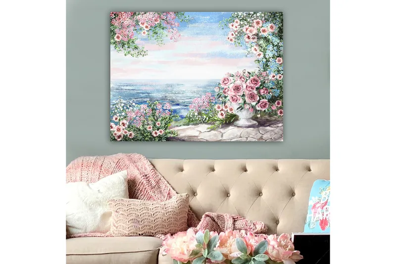 Canvas taulu 70x100 cm - Kaunis kukkapenkki, jossa on suuri ruusuilla täytetty maljakko, meren rannalla kirkkaan taivaan alla - Vaaleanpunainen / Vihreä / Sininen - Sisustustuotteet - Taulu & taide - Canvas-taulu