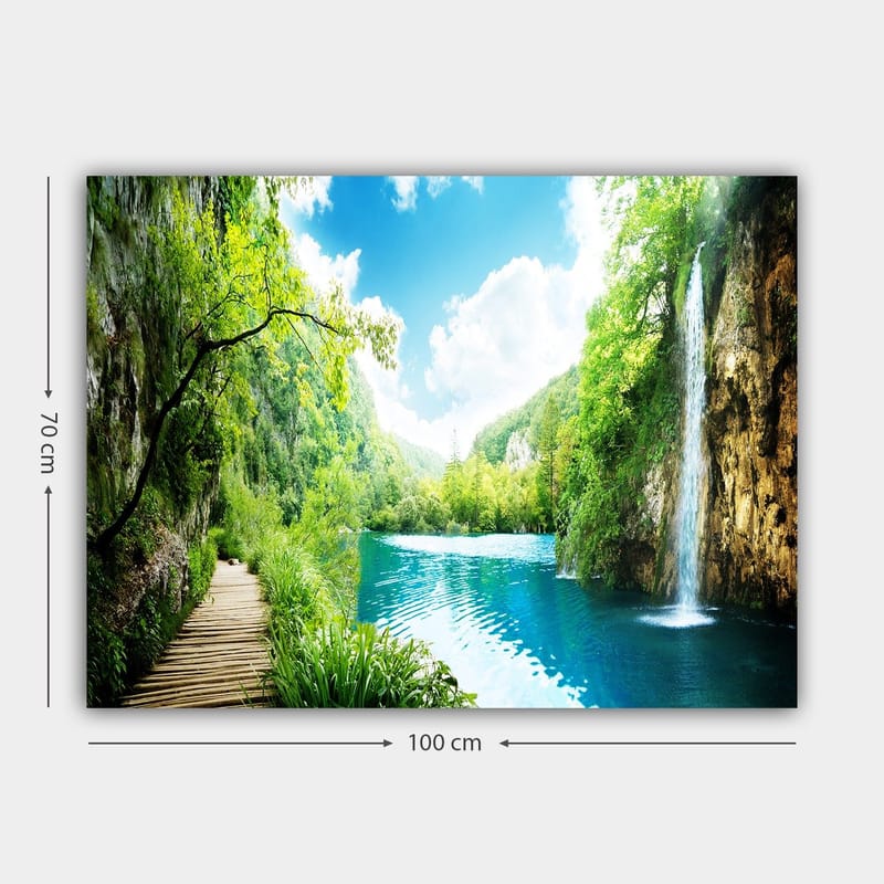 Canvas taulu 70x100 cm - Kaunis luontomaisema vesiputouksella, joka virtaa kirkkaaseen, siniseen järveen rehevän vehreyden ja vuorten ympäröimänä - Vihreä / Sininen - Sisustustuotteet - Taulu & taide - Canvas-taulu