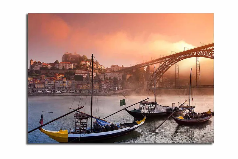 Canvas taulu 70x100 cm - Kaunis näkymä joelle perinteisten veneiden ja majesteettisen sillan ympäröimänä taustalla, värikkäiden talojen ympäröimänä, Oranssi / Sininen / Keltainen