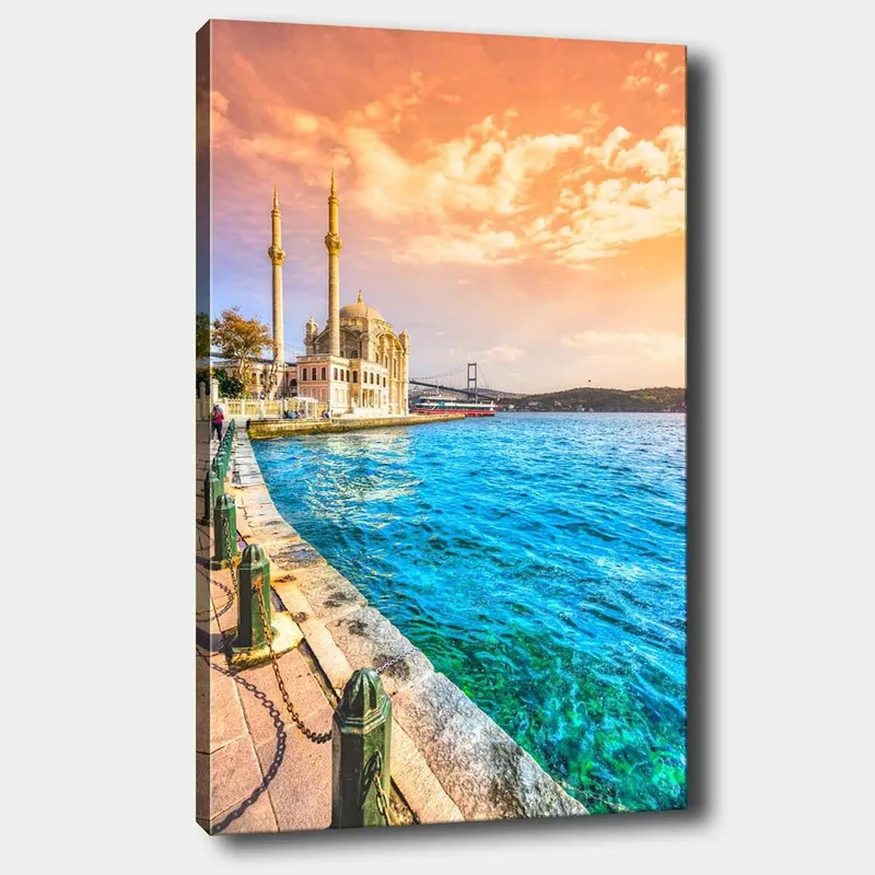 Canvas taulu 70x100 cm - Kaunis näkymä moskeijasta veden äärellä, taustalla silta värikkään taivaan alla, Sininen / Oranssi / Beige