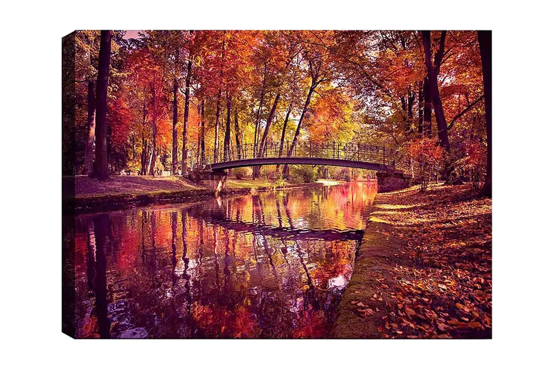 Canvas taulu 70x100 cm - Kaunis syysmaisema, jossa silta ylittää peilimäisen veden pinnan värikkäiden puiden ympäröimänä, Oranssi / Punainen / Keltainen