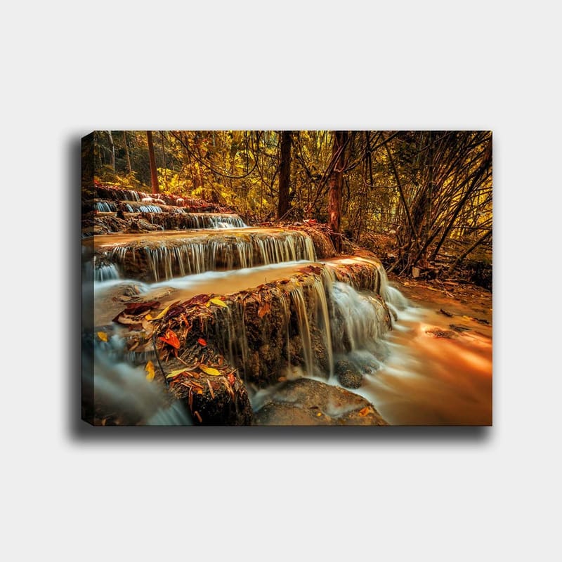 Canvas taulu 70x100 cm - Kaunis vesiputous, joka virtaa useita tasoja alas syksyn värisessä metsässä, Kulta / Ruskea / Oranssi