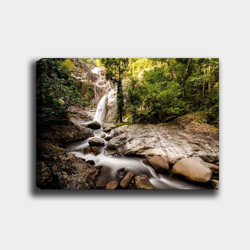 Canvas taulu 70x100 cm - Kaunis vesiputousmaisema rehevän vehreyden ja lohkareiden ympäröimänä, Vihreä / Harmaa / Ruskea