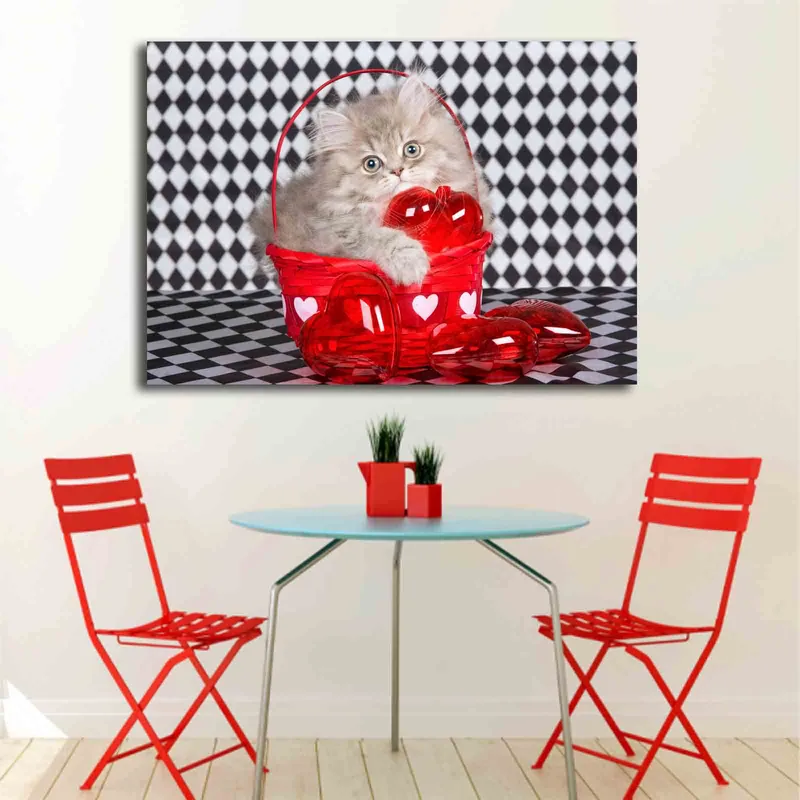 Canvas taulu 70x100 cm - Kissanpentu istuu punaisessa korissa, joka on täynnä sydämenmuotoisia koristeita - Punainen / Harmaa - Sisustustuotteet - Taulu & taide - Canvas-taulu