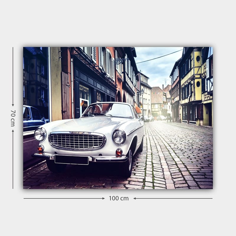 Canvas taulu 70x100 cm - Klassinen valkoinen auto pysäköitynä viehättävälle, vanhanaikaiselle kadulle historiallisten rakennusten ympäröimänä - Valkoinen / Musta / Harmaa - Sisustustuotteet - Taulu & taide - Canvas-taulu