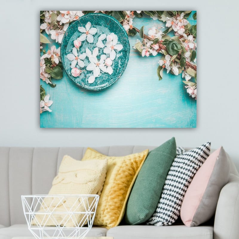 Canvas taulu 70x100 cm - Kukkakulho rehevän vihreän oksan ja kukkien ympäröimänä vaaleansinisellä pohjalla - Turkoosi / Valkoinen / Vaaleanpunainen - Sisustustuotteet - Taulu & taide - Canvas-taulu