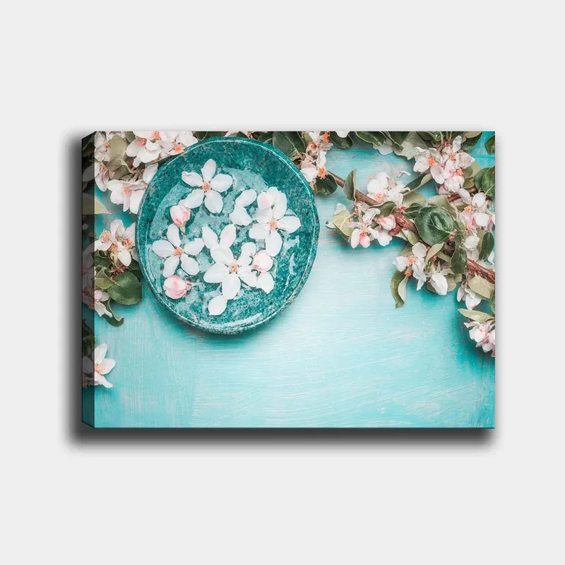Canvas taulu 70x100 cm - Kukkakulho rehevän vihreän oksan ja kukkien ympäröimänä vaaleansinisellä pohjalla, Turkoosi / Valkoinen / Vaaleanpunainen