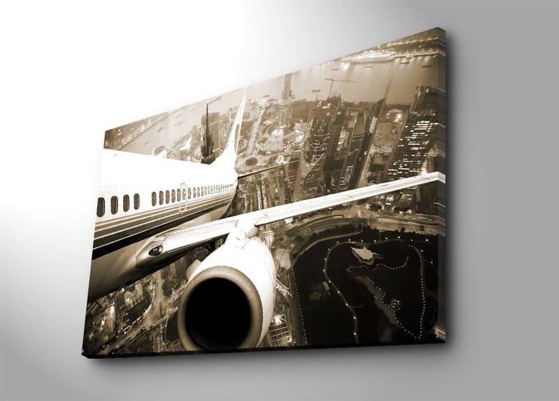 Canvas taulu 70x100 cm - Lentokone leijuu kaupungin yllä hämärässä, Musta / Valkoinen / Harmaa