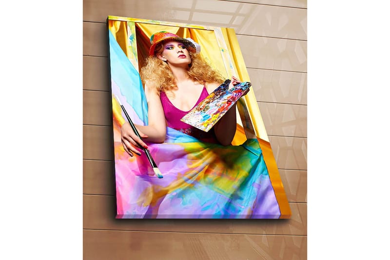 Canvas taulu 70x100 cm - Luova nainen maalaa paletti kädessään, värikkäiden kankaiden ympäröimänä - Vaaleanpunainen / Sininen / Keltainen - Sisustustuotteet - Taulu & taide - Canvas-taulu
