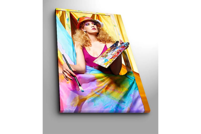 Canvas taulu 70x100 cm - Luova nainen maalaa paletti kädessään, värikkäiden kankaiden ympäröimänä - Vaaleanpunainen / Sininen / Keltainen - Sisustustuotteet - Taulu & taide - Canvas-taulu