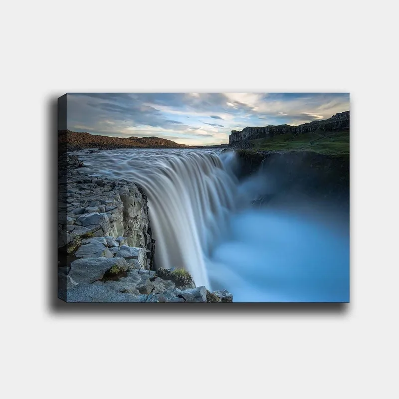 Canvas taulu 70x100 cm - Majesteettinen vesiputous virtaa kallioiden yli luonnonkauniissa ympäristössä, Sininen / Harmaa / Valkoinen