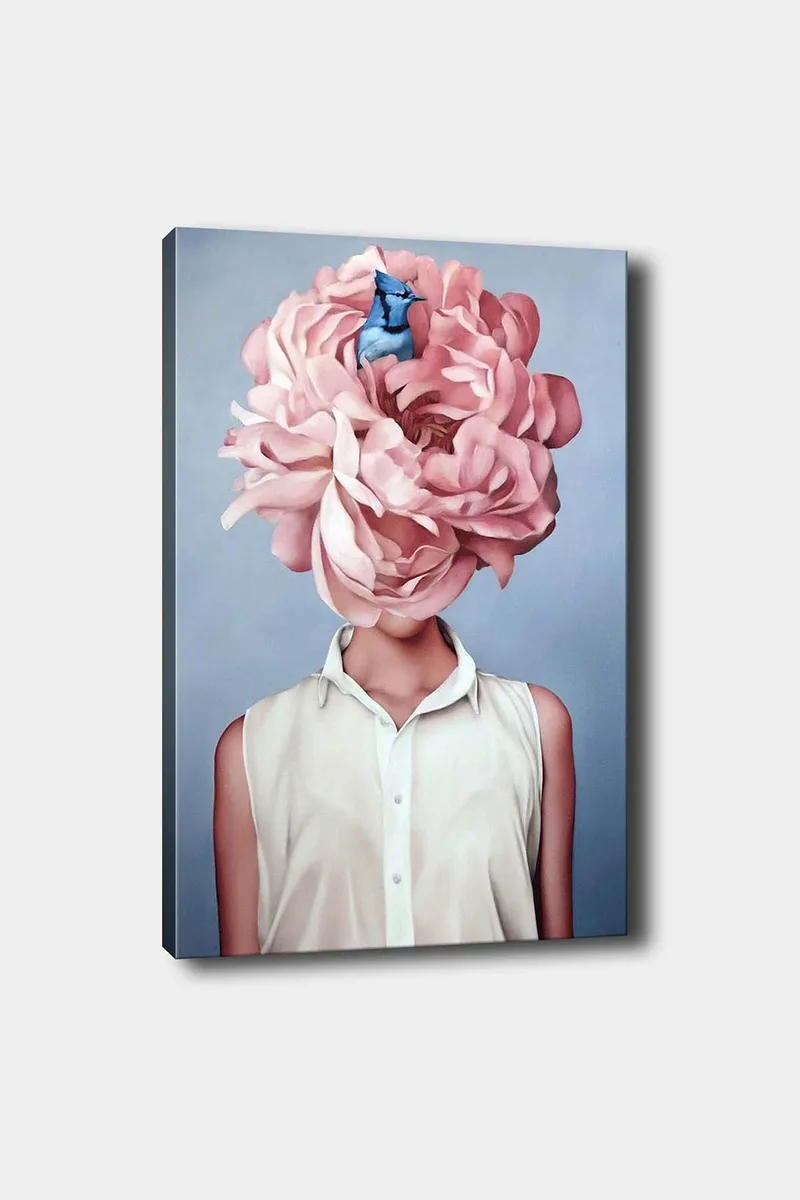 Canvas taulu 70x100 cm - Nainen suuressa vaaleanpunaisessa kukkapäähineessä ja sinisessä linnussa istumassa kukkien keskellä, Vaaleanpunainen / Sininen / Beige