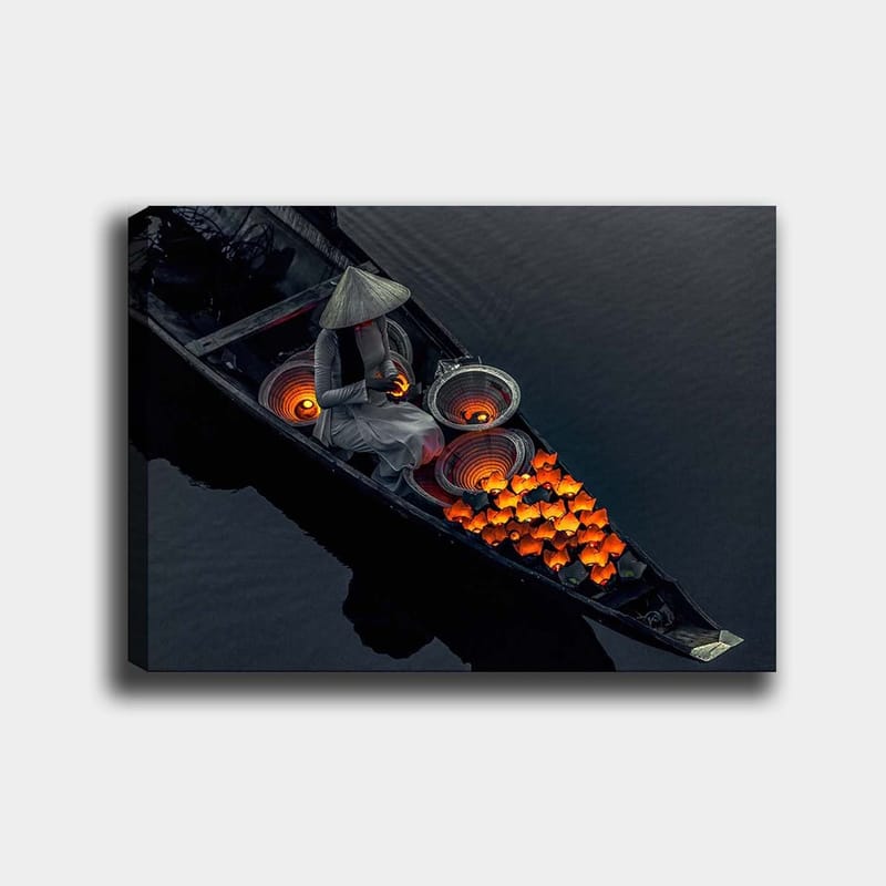 Canvas taulu 70x100 cm - Nainen veneessä ympäröi itsensä kirkkaan oranssilla kalalla ja perinteisillä koreilla, Oranssi / Musta / Harmaa