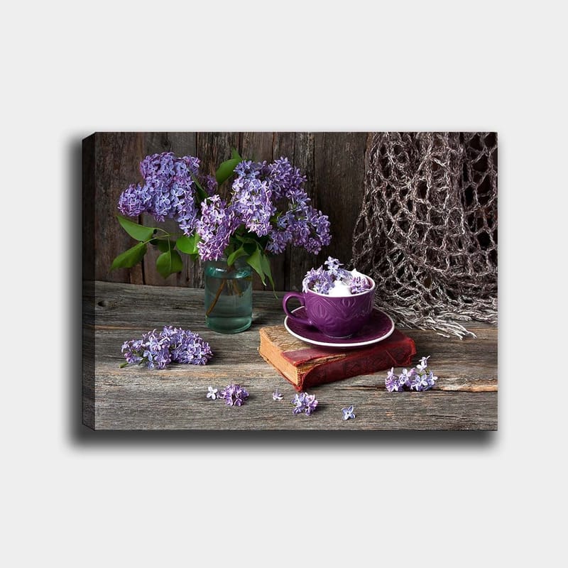 Canvas taulu 70x100 cm - Rauhallinen luontomaalaus, jossa violetteja syreenejä lasimaljakossa ja violetti kuppi vanhan kirjan päällä - Violetti / Vihreä / Ruskea - Sisustustuotteet - Taulu & taide - Canvas-taulu