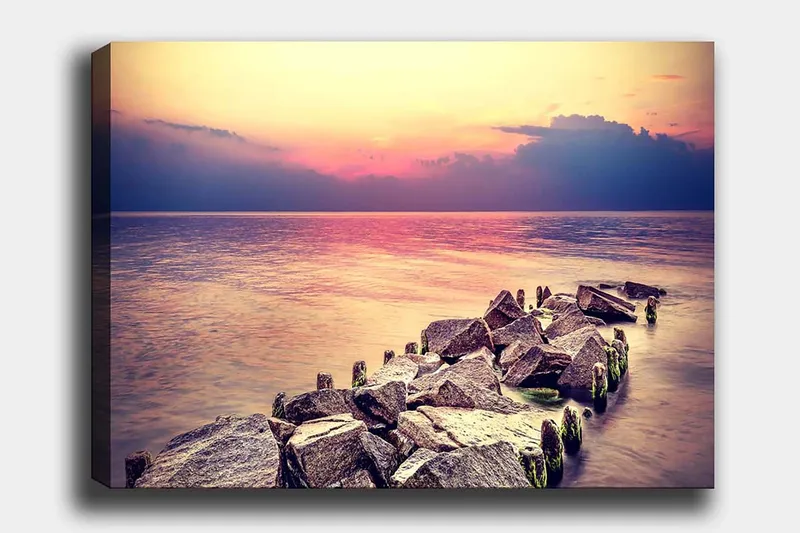Canvas taulu 70x100 cm - Rauhallinen näkymä kallioiselle rannalle auringonlaskun aikaan, Harmaa / Vaaleansininen / Vaaleanpunainen
