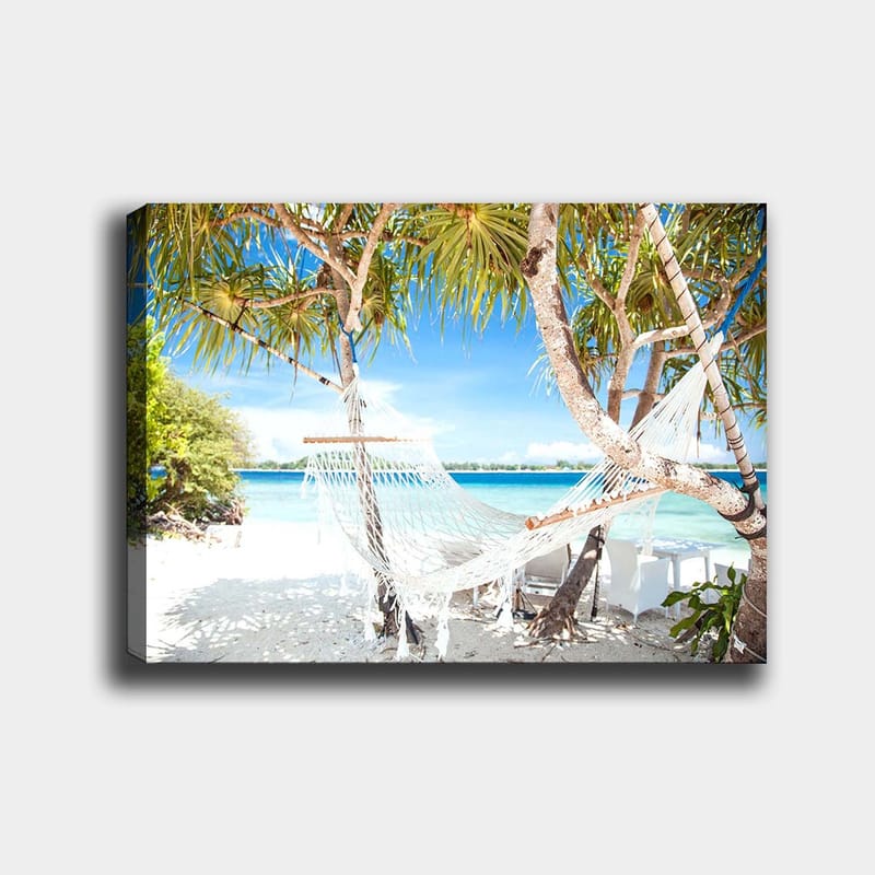 Canvas taulu 70x100 cm - Rentouttava riippumatto palmujen välissä rannalla, jossa on turkoosi vesi ja kirkas sininen taivas, Valkoinen / Sininen / Vihreä
