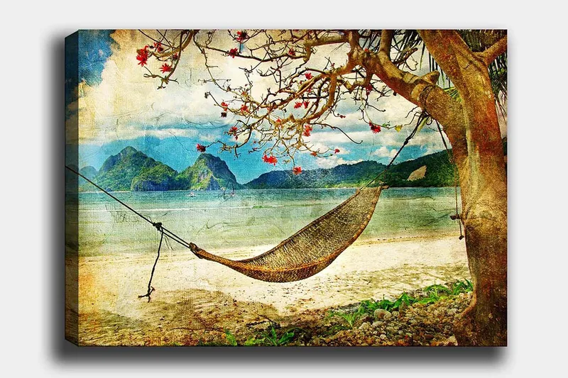 Canvas taulu 70x100 cm - Rentouttava riippumatto puiden oksien välissä kauniilla rannalla, taustalla kaukaiset vuoret, Vihreä / Ruskea / Sininen