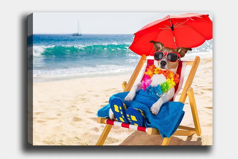 Canvas taulu 70x100 cm - Rentoutunut koira nauttii auringosta rantatuolissa aurinkovarjon alla, Punainen / Sininen / Keltainen