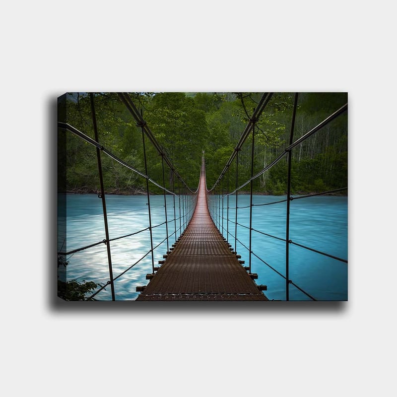 Canvas taulu 70x100 cm - Riippusilta, joka ylittää tyynen, sinisen joen rehevien puiden ympäröimänä, Tummanruskea / Turkoosi / Vihreä