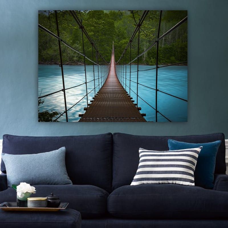 Canvas taulu 70x100 cm - Riippusilta, joka ylittää tyynen, sinisen joen rehevien puiden ympäröimänä - Tummanruskea / Turkoosi / Vihreä - Sisustustuotteet - Taulu & taide - Canvas-taulu