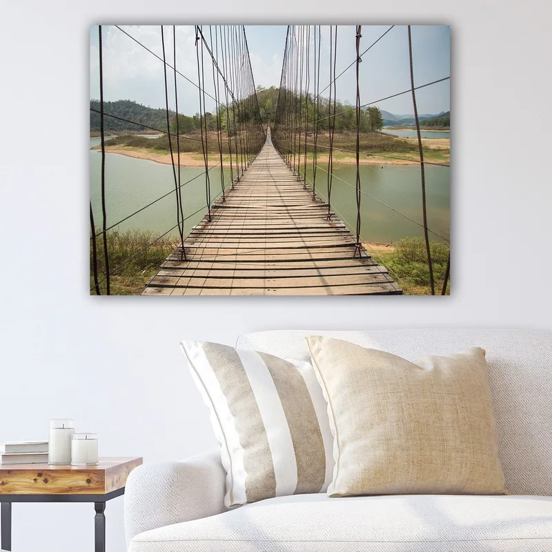 Canvas taulu 70x100 cm - Riippusilta tyynen järven yli, rehevien vihreiden kukkuloiden ympäröimänä, Vihreä / Ruskea / Beige