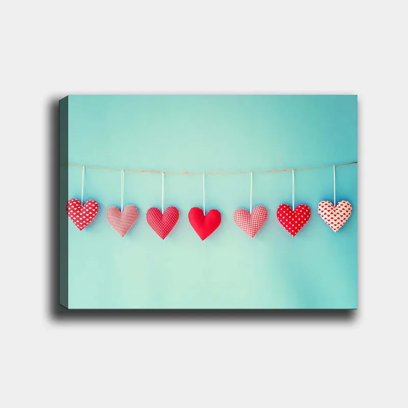 Canvas taulu 70x100 cm - Roikkuvia sydämiä eri kuvioissa ja punaisen sävyissä, Punainen / Vaaleansininen / Valkoinen