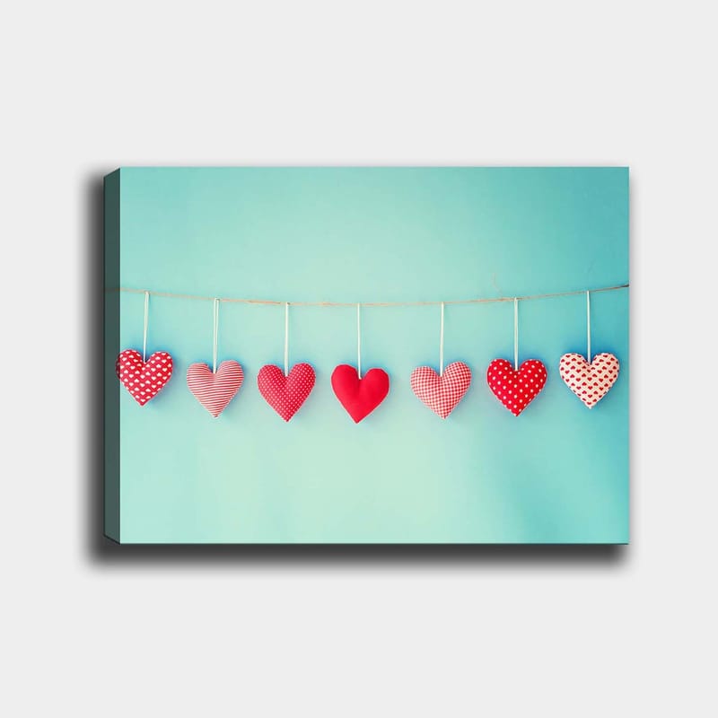 Canvas taulu 70x100 cm - Roikkuvia sydämiä eri kuvioissa ja punaisen sävyissä, Punainen / Vaaleansininen / Valkoinen