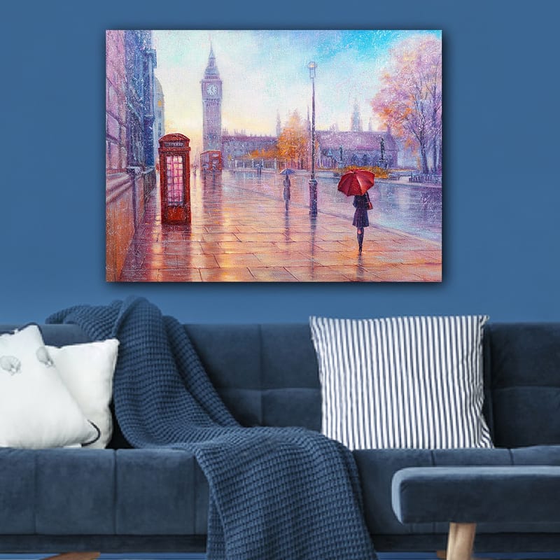 Canvas taulu 70x100 cm - Sateinen kaupunkikuva punaisella puhelinkopilla ja punaisen sateenvarjon omaava henkilö kävelee märällä kadulla - Punainen / Sininen / Oranssi - Sisustustuotteet - Taulu & taide - Canvas-taulu