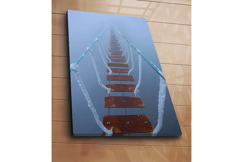 Canvas taulu 70x100 cm - Sumun läpi kurottava riippusilta luo salaperäisen ja etäisen tunnelman - Tummanruskea / Valkoinen / Vaaleansininen - Sisustustuotteet - Taulu & taide - Canvas-taulu
