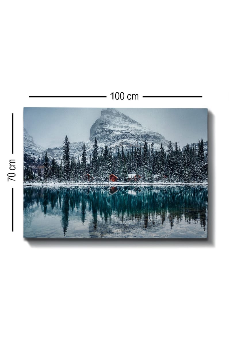 Canvas taulu 70x100 cm - Talvimaisema lumipeitteisillä vuorilla ja peilimäisellä järvellä, jota ympäröivät kuusimetsät ja punaiset mökit - Tummanvihreä / Sininen / Valkoinen - Sisustustuotteet - Taulu & taide - Canvas-taulu