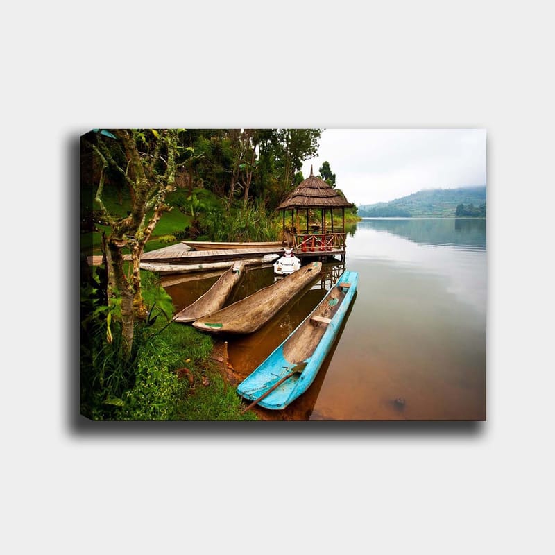 Canvas taulu 70x100 cm - Tyyni järvi, jossa on perinteisiä kanootteja ja paviljonki vehreyden ympäröimänä, Sininen / Ruskea / Vihreä