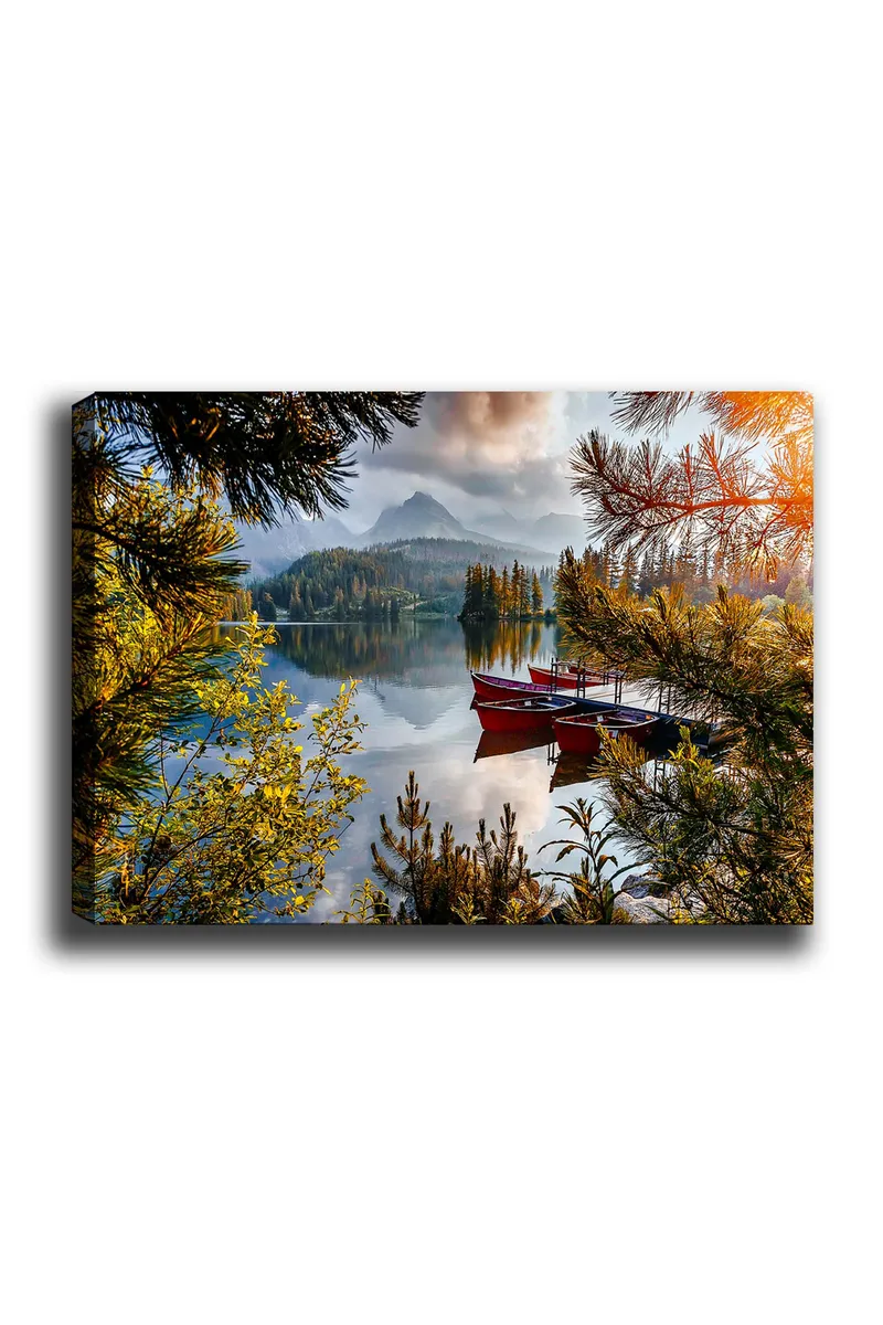 Canvas taulu 70x100 cm - Tyyni järvi ja punainen vene puisella laiturilla, rehevien puiden ja kaukaisten vuorten ympäröimänä, Vihreä / Punainen / Sininen